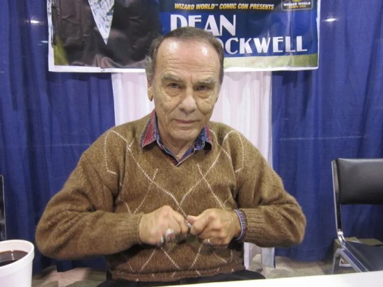Dean Stockwell at con table, glaring into camera while uncapping a pen.