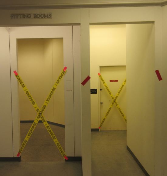 Two department store fitting rooms with yellow walls, both cordoned off with yellow "DO NOT ENTER" tape.