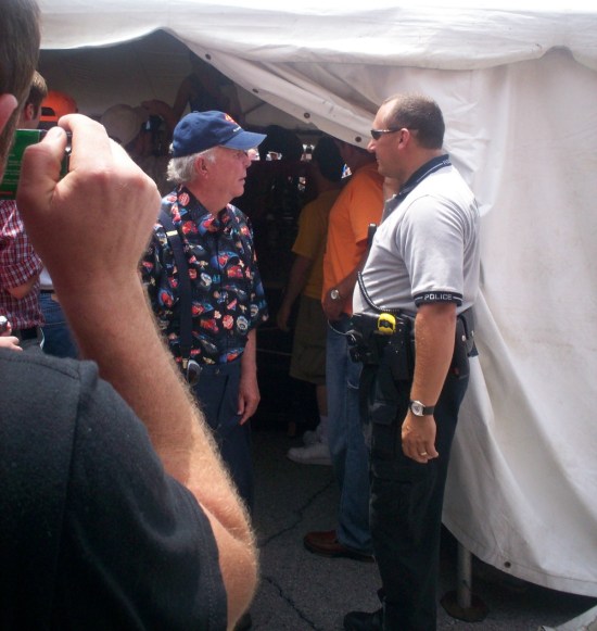 Ned Beatty with blue ball cap, outside a party tent.