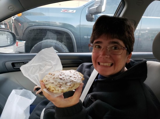 Anne smiling and holding a pecan twirl pastry.