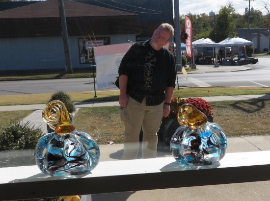 Me standing between a pair of small glass pumpkins on a window shelf.