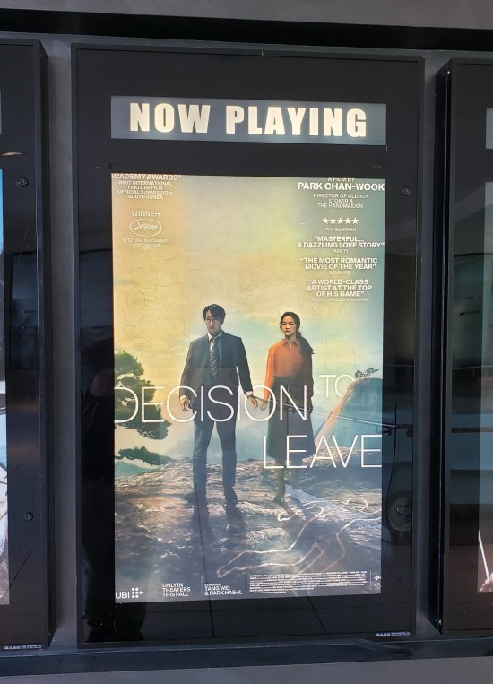 Movie poster for "Decision to Leave" with the two leads atop a mountain, standing next to a victim's chalk outline.