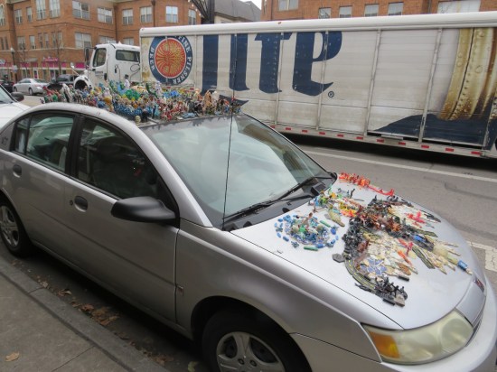 Silver car with toys glued to the roof and hood.