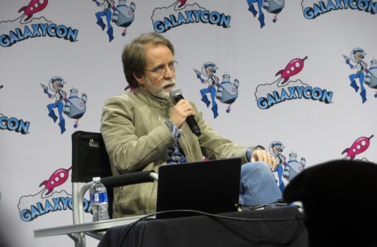 James Arnold Taylor sitting on stage with his laptop of sound samples.