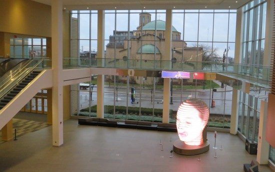 Art in the giant convention center lobby with a church visible through the windows.