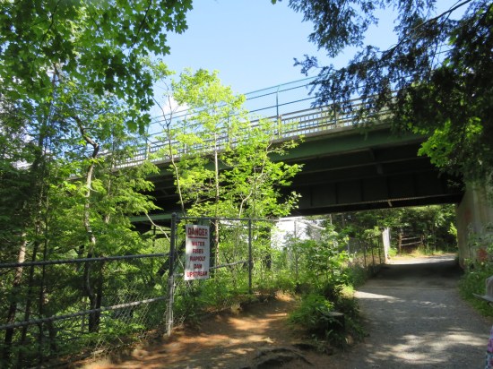 "water rises rapidly dam upstream" says a sign next to the path as it leads under the bridge.
