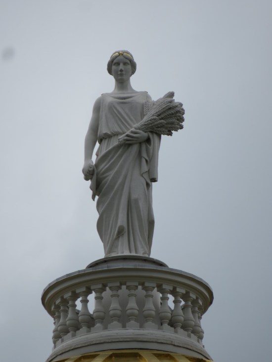 A statue of Ceres atop the capitol dome, holding a grain bouquet.