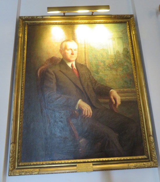 Painting: Presidential guy in a stiff old armchair, hands hanging down at rest. Overhead lights glare annoyingly at the top the painting.