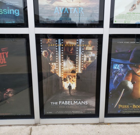 Movie poster for "The Fabelmans", one of several in an outdoor grid.