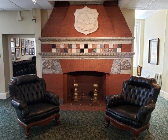 A fireplace and two vinyl chairs.