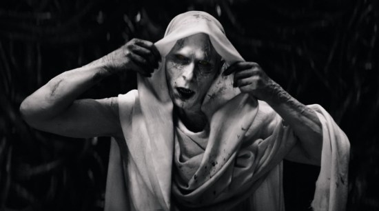 Christian Bale as Gorr the God-Butcher, white-skinned and white-robed, drawing back his hood and imagining us all dead.