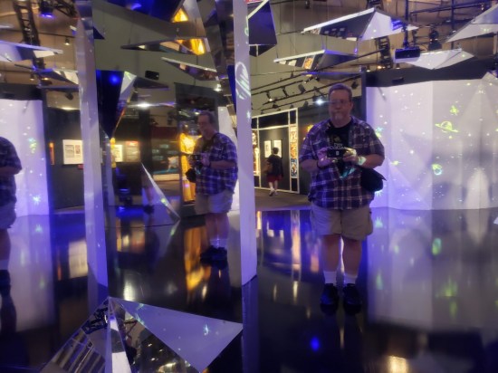 Me in a Marvel museum exhibit surrounded by weird mirrors and purple walls.