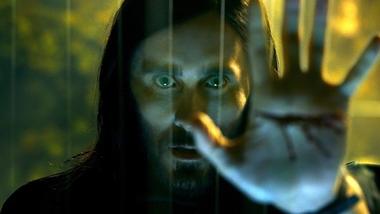 Jared Leto as Michael Morbius holds a hand up to the camera.