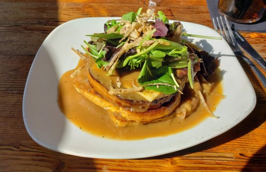 Open-faced meatloaf sandwich on a wooden table in noonday sunlight. See caption.