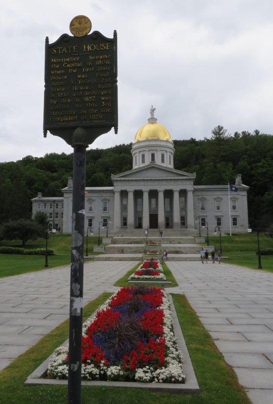 Vermont State House historical marker in front of their colorfully flowered walkway.