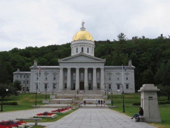 The Vermont State House on a gray day, gold-leaf dome shining and citizens hanging around.