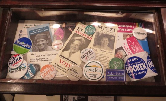 A glass case full of buttons and stickers advertising various women who've run for Vermont offices over the years.