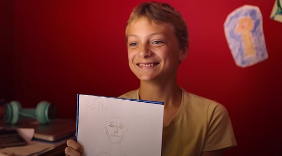 A boy smiles and holds up his sketch of his BFF, who didn't realize it would be intentionally crappy.
