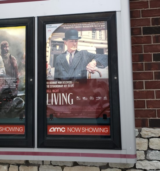 movie poster for "Living" showing Bill Nighy standing before a very British building in dapper suit and bowler, holding a cane and checking his watch.