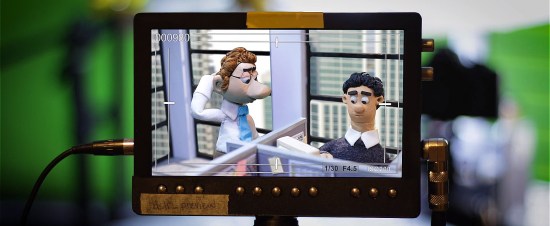 Two stop-motion puppets: a puzzled office worker looks weirdly at his calm, seated coworker who may not be real.