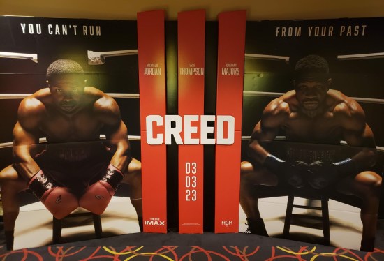 A giant CREED III theater standee with Jordan and Majors' characters sitting in their corners, glowering, ready to fight.