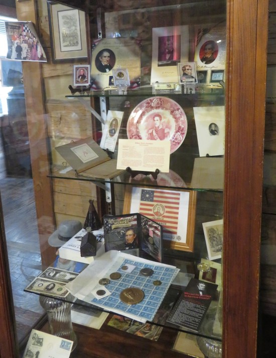 A big glass-doored cabinet filled with dozens of objects with William Henry Harrison's face on them.