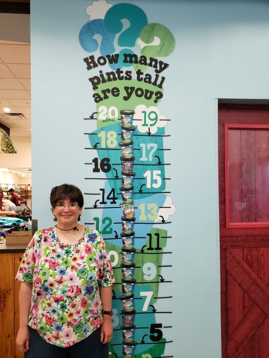 Anne standing next to a height chart made of Ben & Jerry pints.
