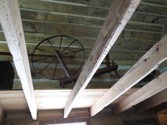 A spinning wheel sitting high up in the rafters for some reason.