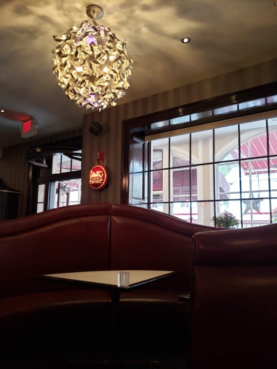 Restaurant table with booth seats covered in red leather or vinyl. On the ceiling is a fancy, spiky light globe.