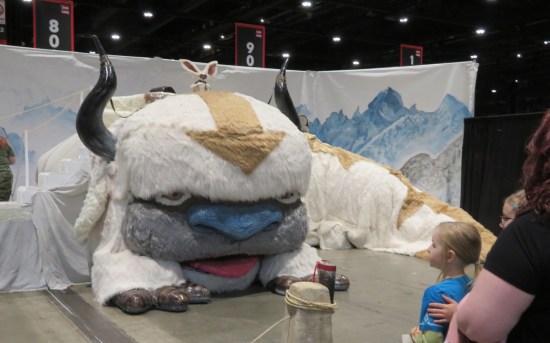 Life-size recreation of a giant furry white bison/manatee friendly hybrid monster with a beige "Last Airbender" arrow pointing down its forehead.