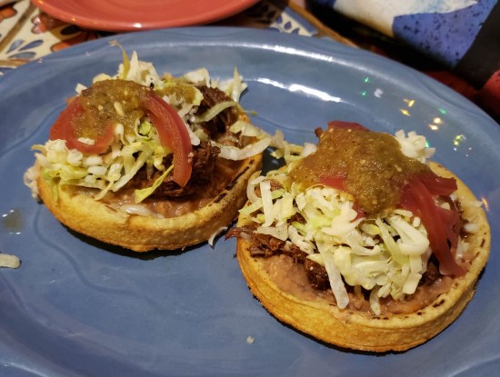 A pair of barbacoa sopes -- refer to caption.