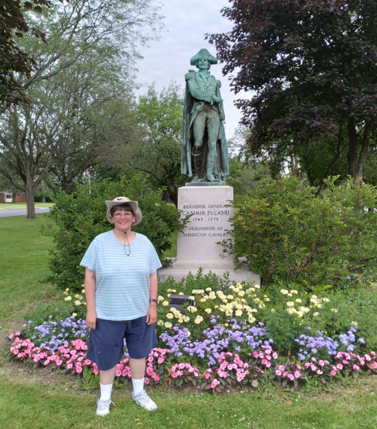 Anne in front of a statue of a Polish military commander on a five-foot pedestal surrounded by pretty flowers.