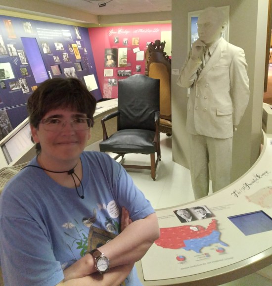 My wife poses with a white suit on a mannequin. Sisplay cases bedeck all the walls in the back.