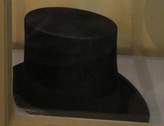 A jet-black top hat in a display case.