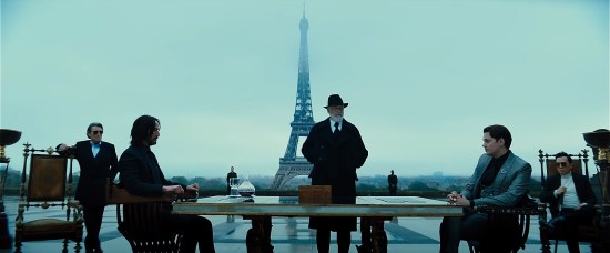 Several cast members posing several blocks away from the Eiffel Tower on a blue-filtered morning.