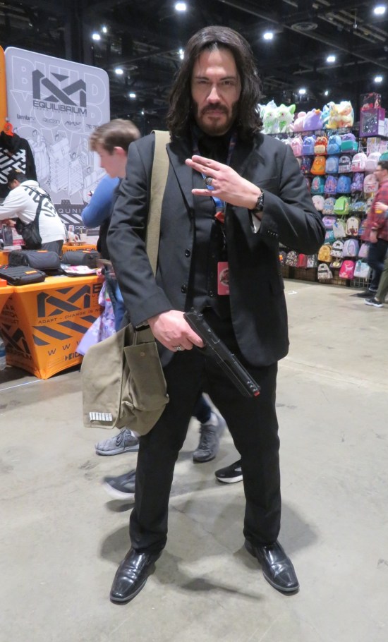 cosplay: John Wick with gun, ring, and missing finger.