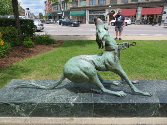 A metal sculpture of an unhappy greyhound straining against an invisible leash. Way behind it, I'm standing there with a puzzled expression and scratching my head.
