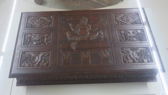 A wooden cigar box with creature-looking pictures engraved in the lid.