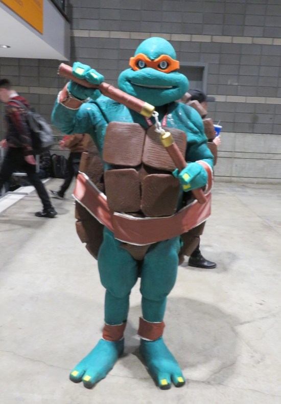 cosplay: Michaelangelo from the Teenage Mutant Ninja Turtles, wielding nunchaku.