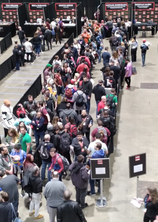 A long, crowded autograph line for Michael Rosenbaum. Aisles on either side of his line are empty.