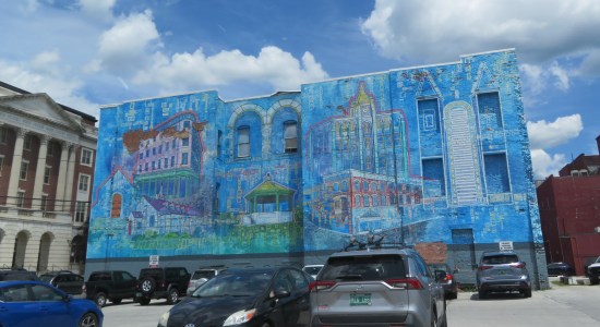 A large two-story commercial building with a large mural depicting select constructs from downtown Rutland itself, mostly in blue.