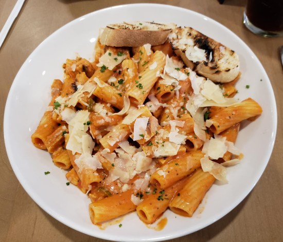 A plate of Chicken Rigatoni with large parmesan shards on top.