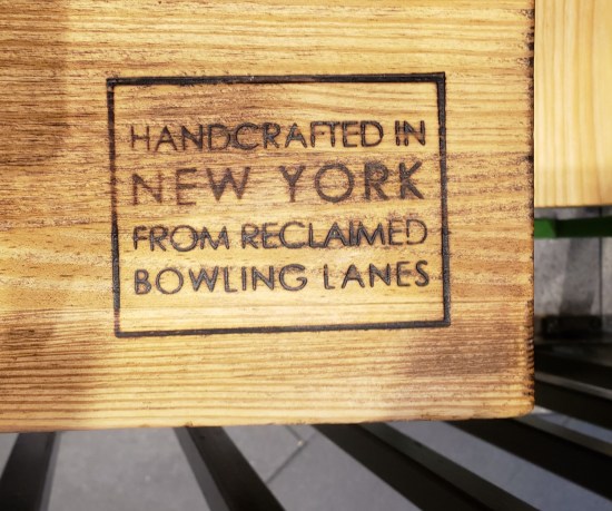 Label etched into wooden table: "Handcrafted in New York from reclaimed bowling lanes."