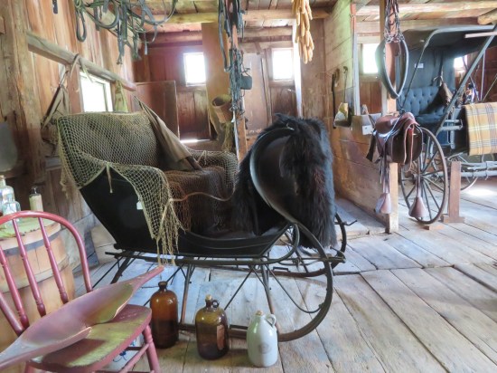 A black sleigh parked inside a wooden garage.