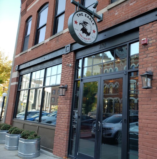 The brick building housing The Eagle Food & Beer Hall. A round sign has an eagle head on it.