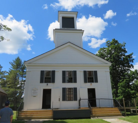 a restored church with white siding and a chimney.