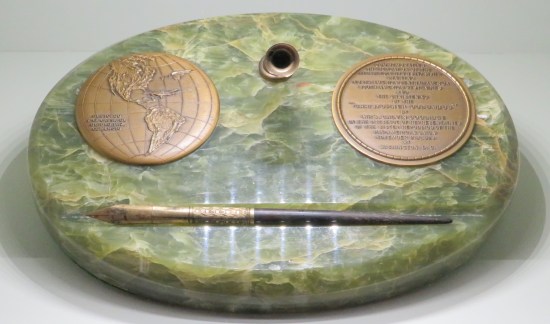 Fancy fountain pen desk stored in a green onyx oval with tiny bronze plaques on it.