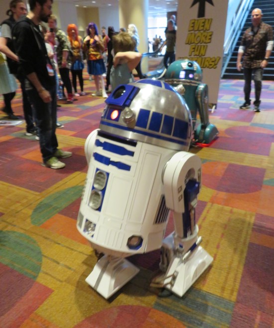 A remote-controlled life-size R2D2, plus another droid wheeling around behind it.