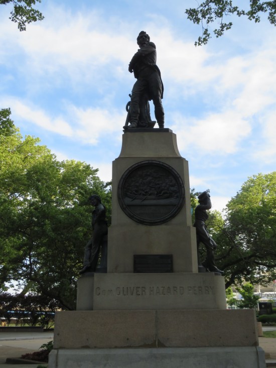 A tall statue of Oliver Hazard Perry on a pedestal with a few soldier statues at the base.