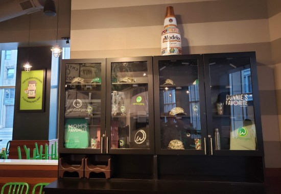 Glass cases filled with Wahlburgers merchandise like hats, shirts and tote bags.